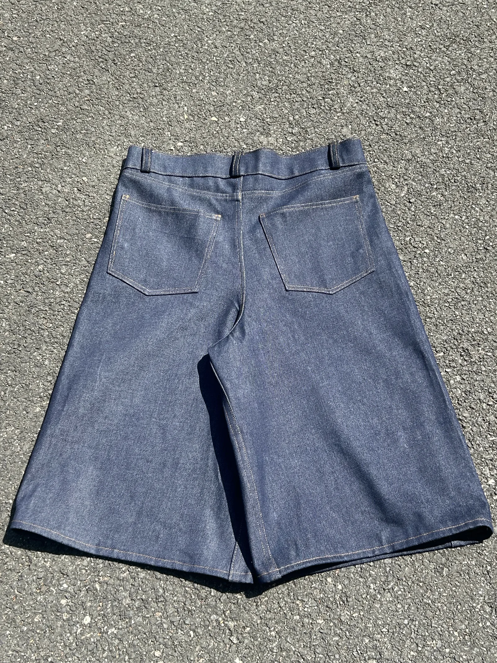 Face arrière d’un pantalon en denim brut posé sur l’asphalte